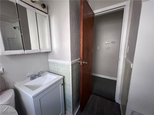 bathroom with vanity, tile walls, and toilet