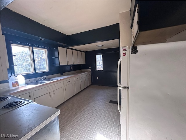 kitchen with white cabinets, white fridge, and sink