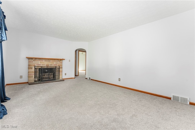 unfurnished living room featuring carpet flooring, a fireplace, and a textured ceiling