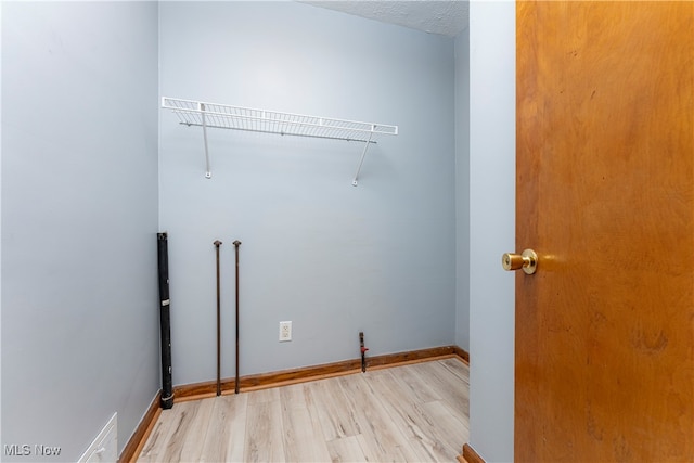 laundry area featuring a textured ceiling and light hardwood / wood-style flooring