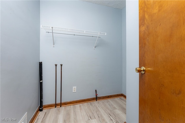 laundry room featuring washer hookup, a textured ceiling, and light hardwood / wood-style flooring