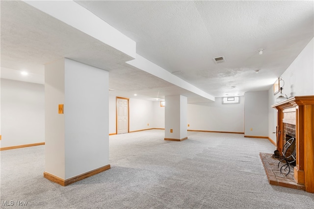 basement featuring a fireplace, light colored carpet, and a textured ceiling