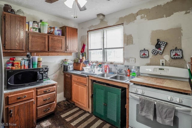 kitchen with ceiling fan, white gas stove, and sink