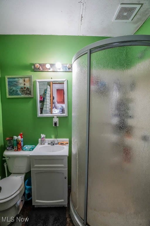 bathroom featuring vanity, toilet, and a shower with shower door