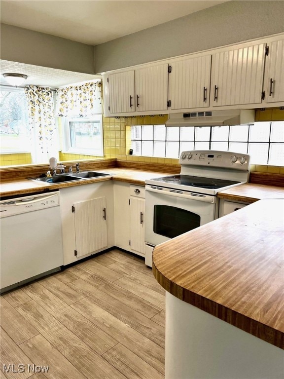 kitchen with a healthy amount of sunlight, light wood-type flooring, white appliances, and sink