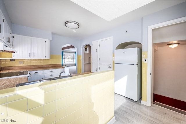 kitchen featuring light wood-style floors, white cabinets, backsplash, tile counters, and freestanding refrigerator