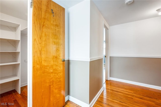 corridor with wood finished floors and baseboards