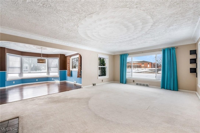 unfurnished living room featuring carpet floors, plenty of natural light, and visible vents