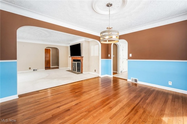 unfurnished room with arched walkways, visible vents, and wood finished floors