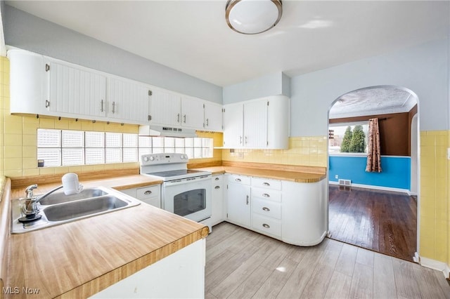 kitchen with white cabinets, electric stove, light countertops, under cabinet range hood, and a sink