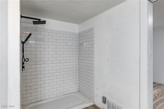 bathroom featuring tiled shower / bath, a textured ceiling, and hardwood / wood-style flooring