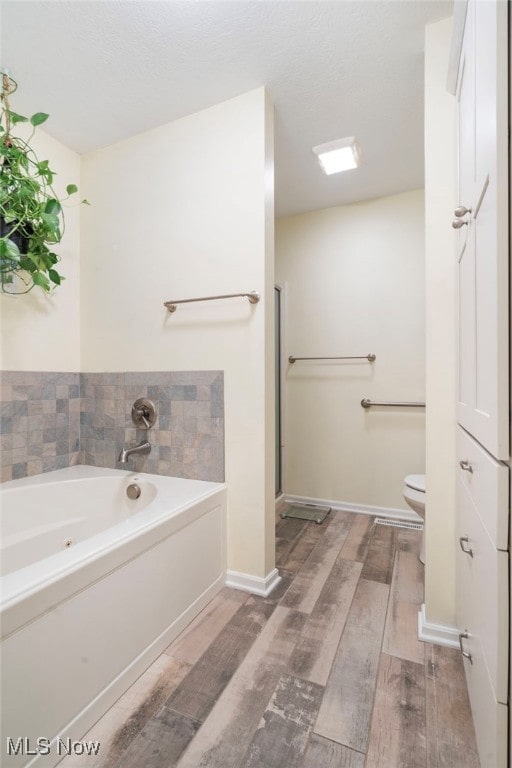 bathroom with a washtub, wood-type flooring, and toilet