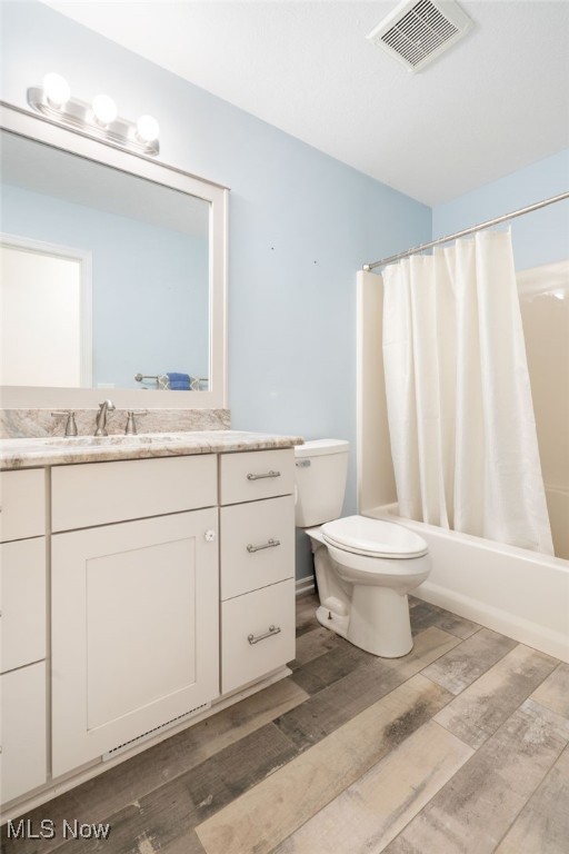 full bathroom featuring hardwood / wood-style floors, vanity, toilet, and shower / tub combo