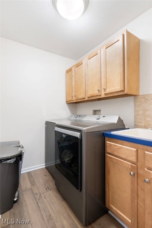 washroom featuring cabinets, independent washer and dryer, and light hardwood / wood-style flooring