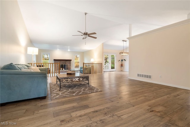 living room featuring lofted ceiling, a brick fireplace, ceiling fan, and dark wood-type flooring