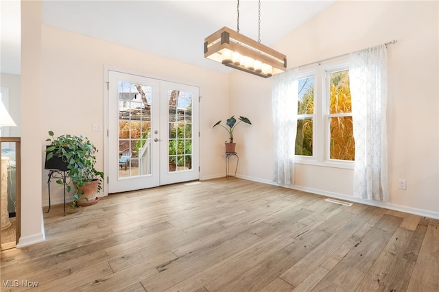 unfurnished dining area featuring french doors, a healthy amount of sunlight, lofted ceiling, and light hardwood / wood-style floors