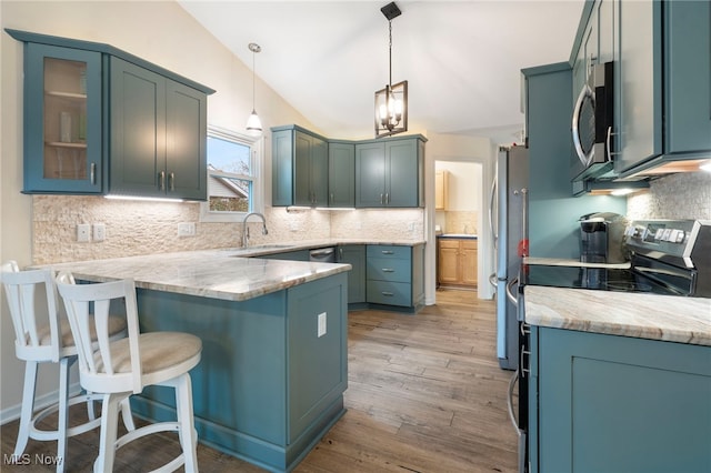 kitchen featuring decorative light fixtures, stainless steel appliances, light hardwood / wood-style flooring, and tasteful backsplash