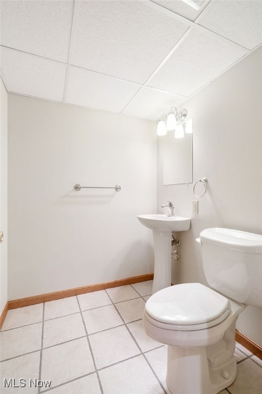 bathroom with toilet, a paneled ceiling, and tile patterned floors