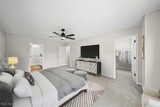 carpeted bedroom with a walk in closet, ensuite bath, a closet, and ceiling fan