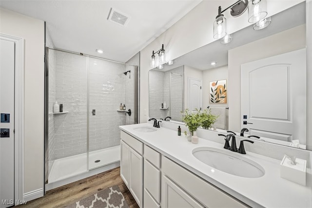 bathroom with hardwood / wood-style floors, vanity, and an enclosed shower
