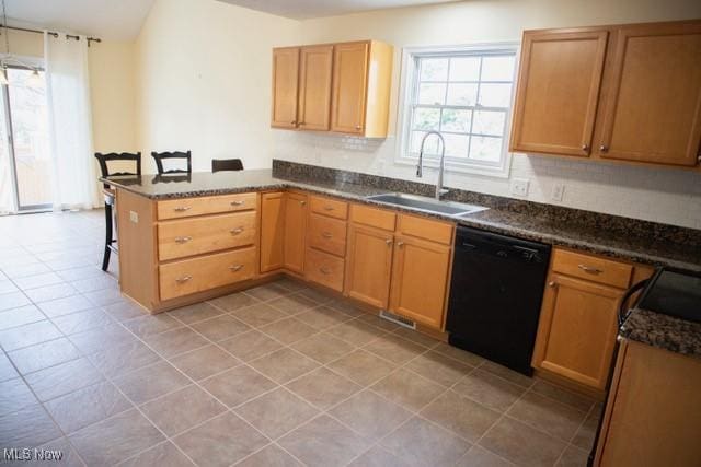 kitchen with black appliances, sink, dark stone countertops, kitchen peninsula, and a breakfast bar area