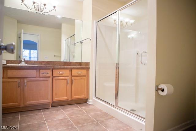 bathroom featuring a chandelier, vanity, tile patterned floors, and walk in shower