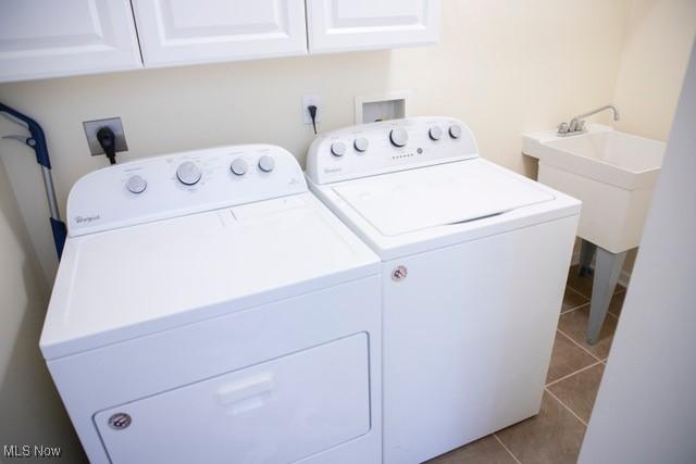 laundry area featuring cabinets, sink, light tile patterned floors, and washer and dryer