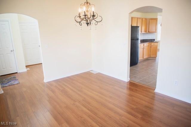 unfurnished dining area featuring a notable chandelier and wood-type flooring