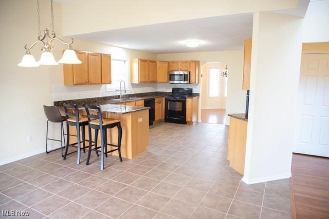 kitchen featuring kitchen peninsula, a healthy amount of sunlight, hanging light fixtures, and black appliances