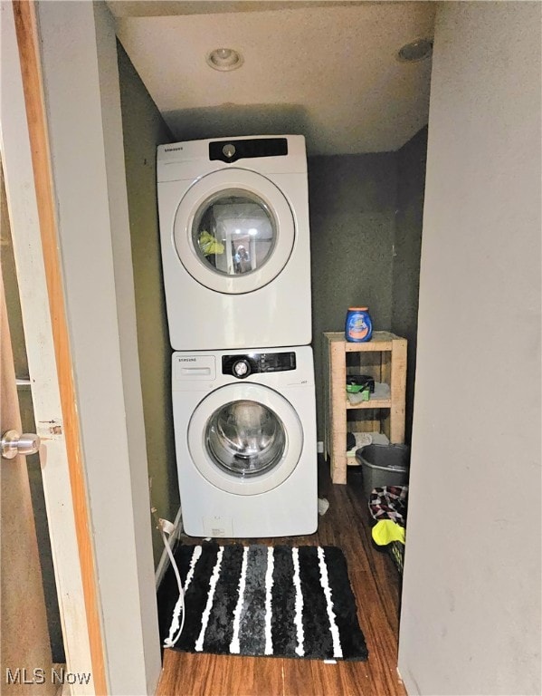 clothes washing area with stacked washer and dryer and dark wood-type flooring