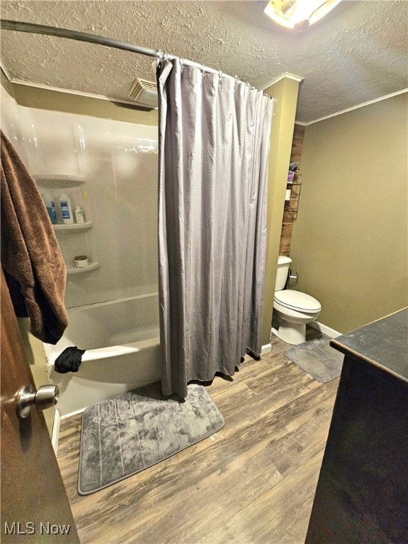 full bathroom with wood-type flooring, a textured ceiling, toilet, shower / tub combo with curtain, and vanity