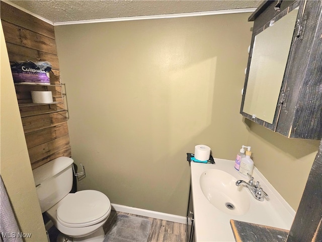 bathroom featuring a textured ceiling, vanity, hardwood / wood-style flooring, toilet, and wood walls