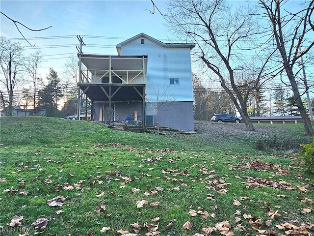 back of property with a balcony, a yard, and central AC