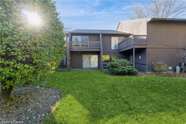 rear view of property with a yard and a balcony