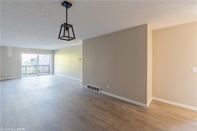 spare room featuring hardwood / wood-style floors and a textured ceiling