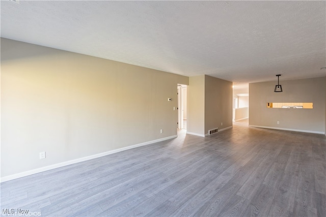 empty room with hardwood / wood-style floors and a textured ceiling