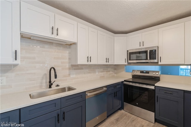 kitchen featuring sink, white cabinets, light hardwood / wood-style floors, and appliances with stainless steel finishes