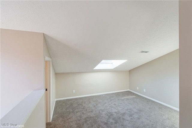 additional living space featuring carpet flooring and lofted ceiling with skylight