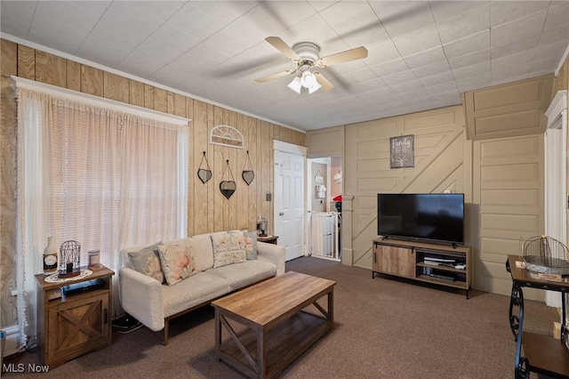 carpeted living room featuring wood walls, ceiling fan, and ornamental molding