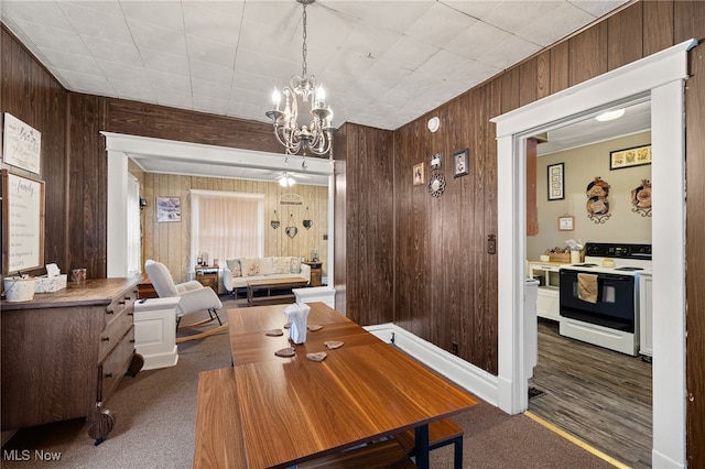 carpeted dining room with a chandelier and wooden walls