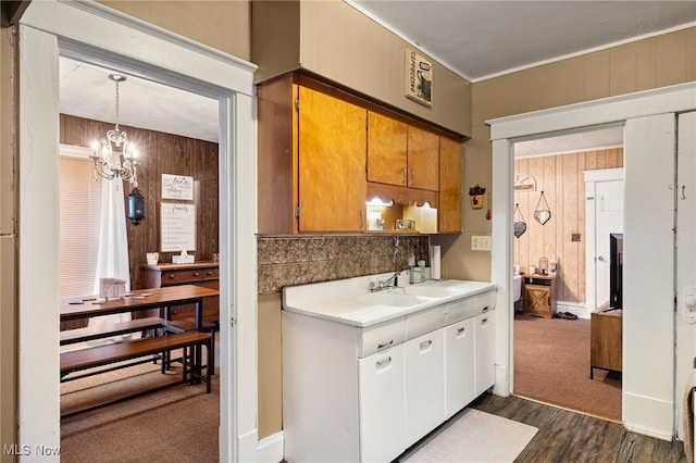 kitchen with wooden walls, hanging light fixtures, dark hardwood / wood-style floors, and an inviting chandelier