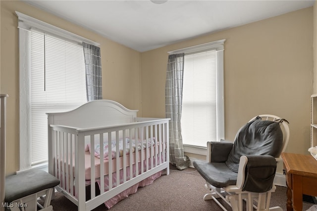 carpeted bedroom featuring multiple windows and a crib