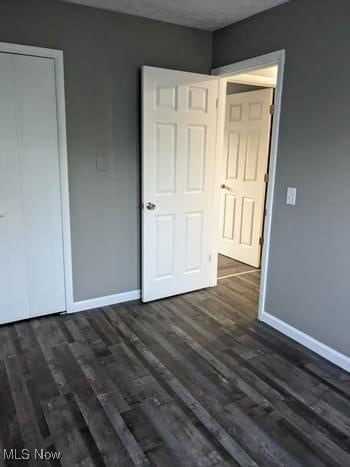 unfurnished bedroom with a closet and dark hardwood / wood-style flooring