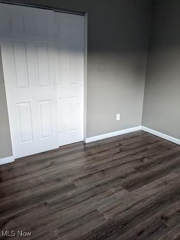 unfurnished bedroom with dark hardwood / wood-style flooring and a closet