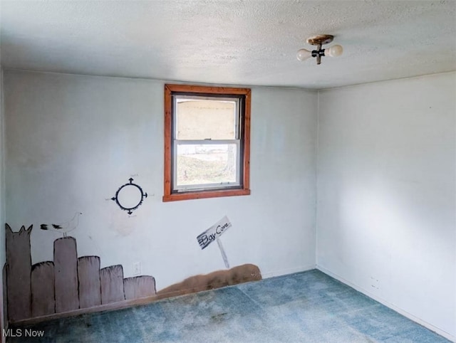 carpeted empty room featuring a textured ceiling