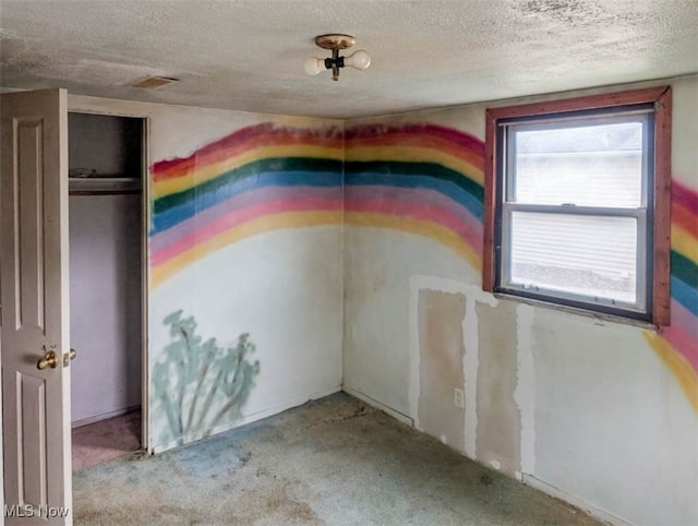 carpeted empty room featuring a textured ceiling