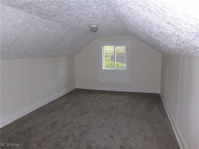 bonus room with a textured ceiling, dark carpet, and vaulted ceiling