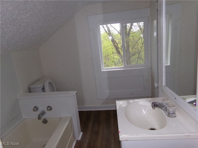 bathroom with vanity, lofted ceiling, toilet, wood-type flooring, and a tub