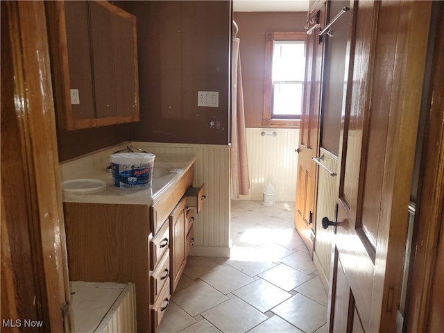 bathroom featuring tile patterned floors, vanity, and wooden walls