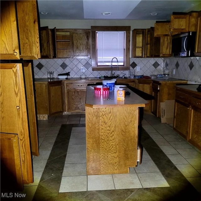 kitchen featuring sink, decorative backsplash, a center island, and light tile patterned floors